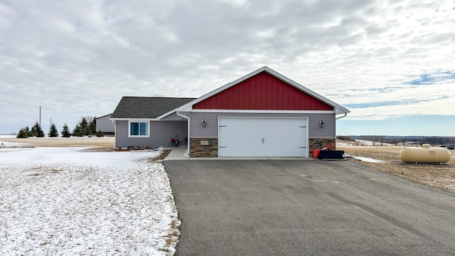 view of front of house featuring a garage, stone siding, driveway, and board and batten siding