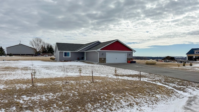 view of front of property with aphalt driveway, stone siding, and a garage