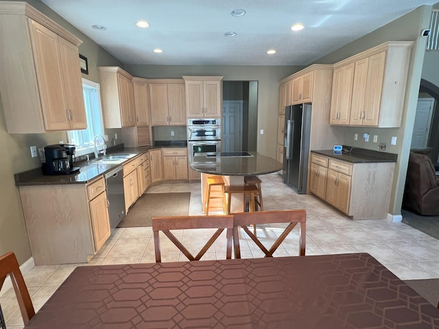 kitchen featuring dark countertops, light tile patterned flooring, stainless steel appliances, a sink, and recessed lighting