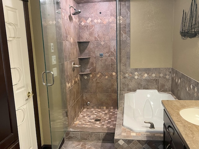 bathroom with a stall shower, a textured wall, a garden tub, and vanity