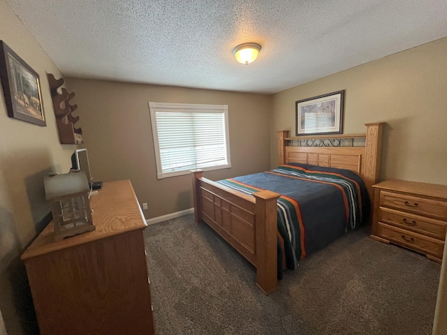 bedroom featuring dark carpet, a textured ceiling, and baseboards