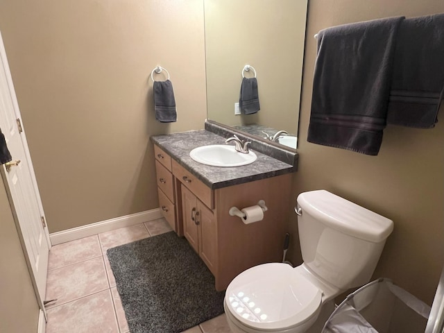 bathroom with toilet, vanity, baseboards, and tile patterned floors