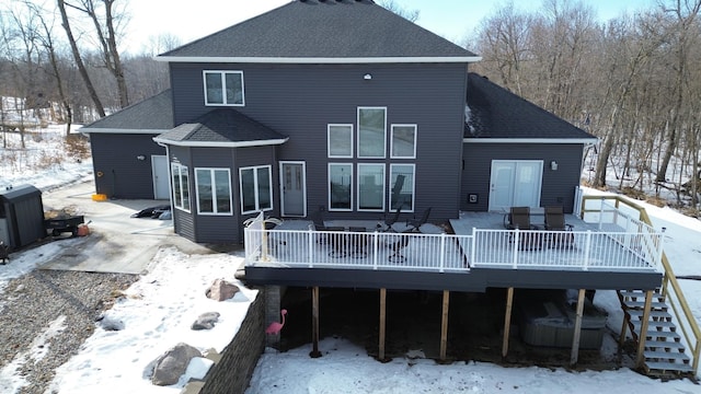 snow covered property featuring a deck, roof with shingles, and stairs