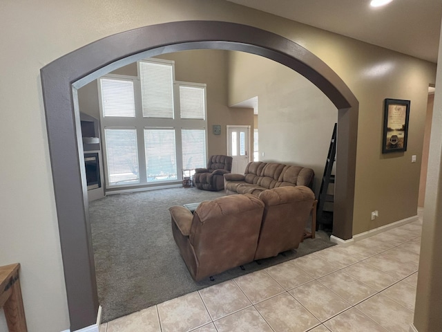 living room with light carpet, light tile patterned floors, baseboards, and arched walkways