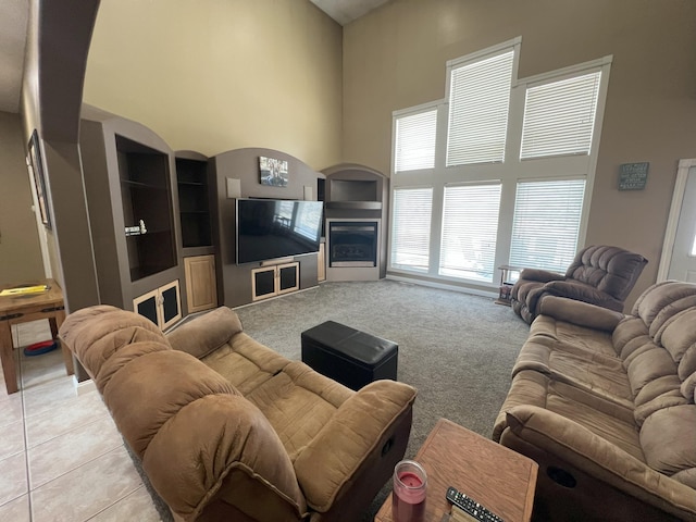 living area with light colored carpet, a fireplace, a high ceiling, and light tile patterned floors