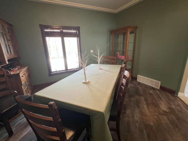 dining space with dark wood-type flooring, visible vents, crown molding, and baseboards