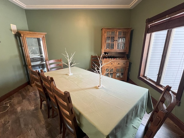 dining area featuring dark wood-style floors, a healthy amount of sunlight, crown molding, and baseboards