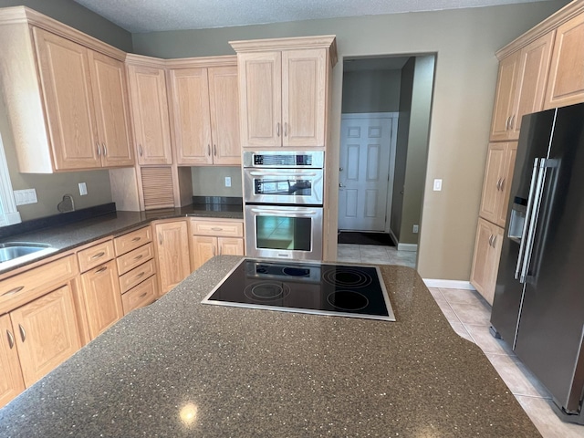 kitchen featuring light tile patterned floors, black appliances, dark stone counters, and light brown cabinets