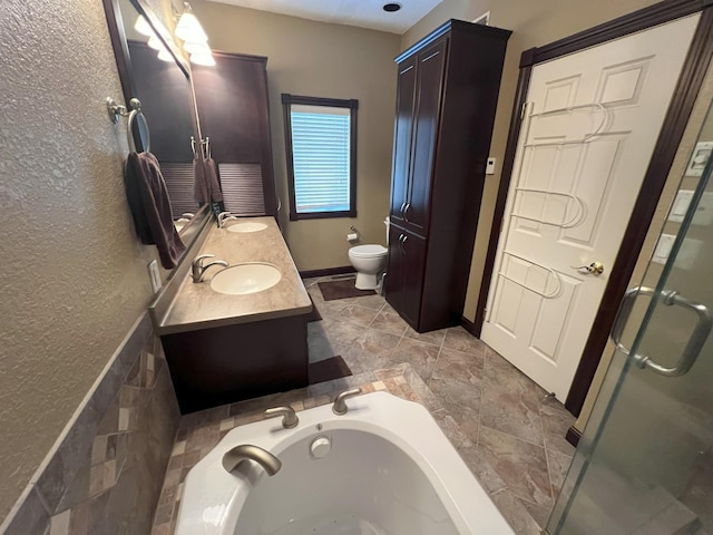 bathroom with toilet, a shower stall, double vanity, and a sink