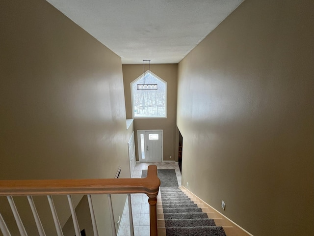 stairway featuring a towering ceiling and baseboards