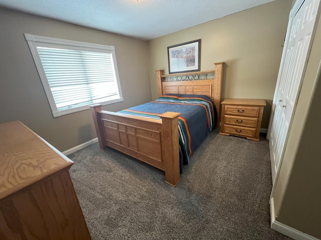 bedroom with baseboards, dark colored carpet, and a textured ceiling