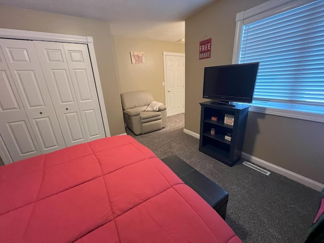 carpeted bedroom with a closet, visible vents, and baseboards