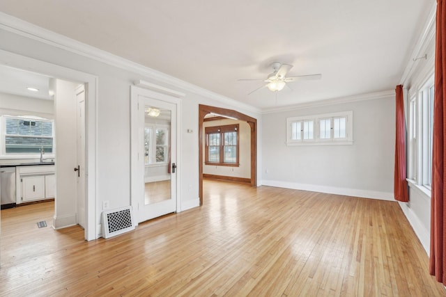 spare room featuring ornamental molding, light wood-type flooring, visible vents, and a ceiling fan