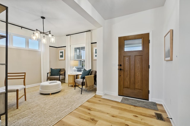 entrance foyer with visible vents, a chandelier, light wood-style flooring, and baseboards