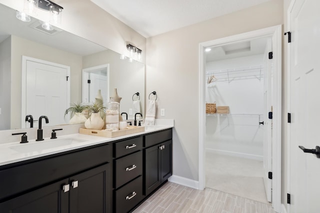 full bath featuring double vanity, a spacious closet, baseboards, and a sink