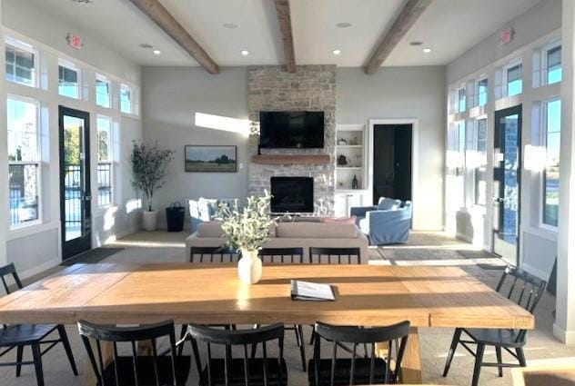 dining room featuring baseboards, a fireplace, a high ceiling, and beamed ceiling