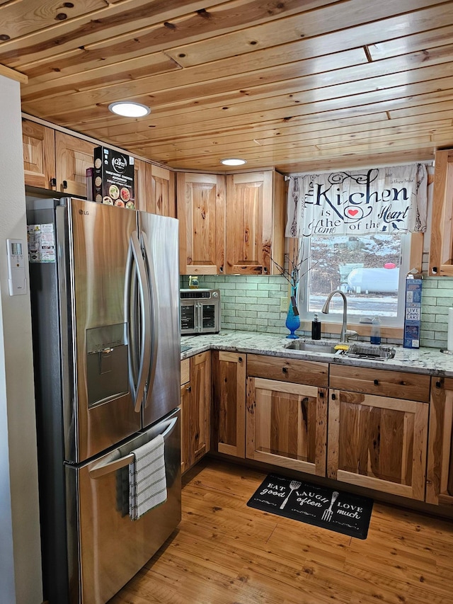 kitchen with tasteful backsplash, stainless steel fridge with ice dispenser, wooden ceiling, light stone countertops, and light wood-style floors