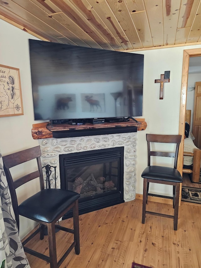 interior space with wooden ceiling, light wood-style flooring, and a glass covered fireplace