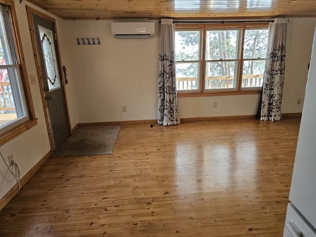 foyer with baseboards, light wood finished floors, and a wall mounted AC