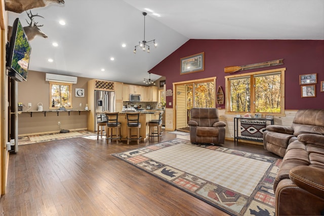 living room with high vaulted ceiling, recessed lighting, a wall mounted AC, dark wood finished floors, and an inviting chandelier