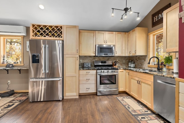 kitchen featuring stainless steel appliances, light brown cabinetry, a wall mounted AC, and a sink