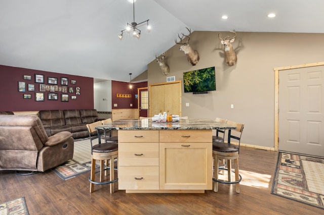 kitchen with a kitchen island, a kitchen breakfast bar, dark wood-type flooring, open floor plan, and light brown cabinets