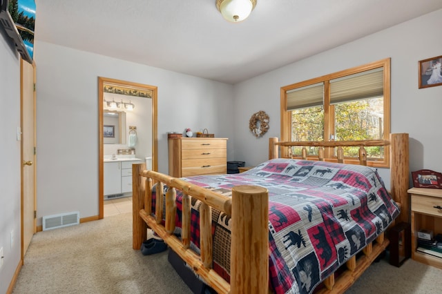 carpeted bedroom featuring ensuite bath and visible vents