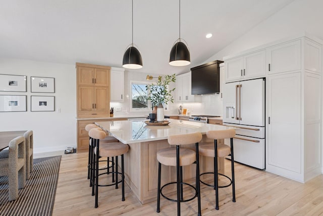 kitchen featuring lofted ceiling, light countertops, decorative backsplash, high quality appliances, and light wood-type flooring