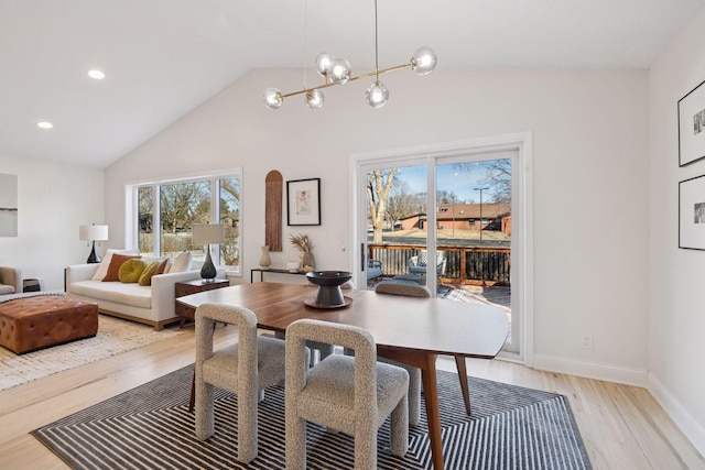 dining space featuring arched walkways, an inviting chandelier, light wood-style floors, vaulted ceiling, and baseboards