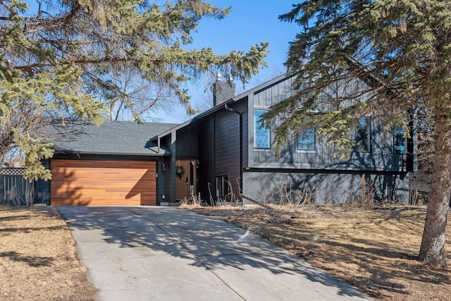 view of front of home with concrete driveway, a chimney, and an attached garage