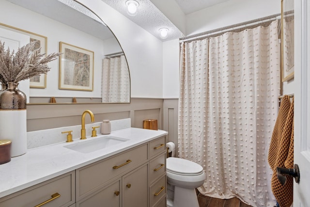 bathroom with curtained shower, toilet, a textured ceiling, vanity, and wood finished floors