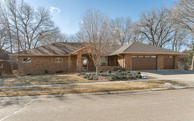 ranch-style house featuring a garage, brick siding, roof with shingles, and concrete driveway