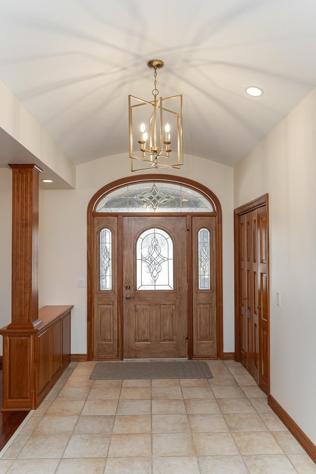 entryway featuring a chandelier, baseboards, ornate columns, and vaulted ceiling