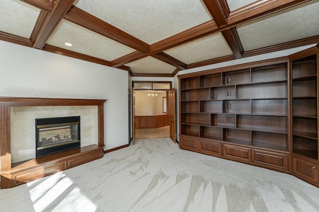 unfurnished living room with coffered ceiling, an inviting chandelier, a fireplace, beamed ceiling, and carpet flooring