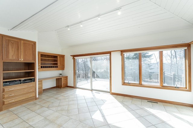 interior space with lofted ceiling, light tile patterned floors, built in desk, and a wealth of natural light