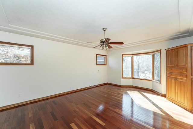 unfurnished room featuring baseboards, a raised ceiling, hardwood / wood-style floors, and a ceiling fan