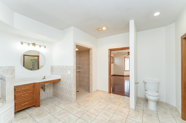 full bathroom with vanity, toilet, a tile shower, and tile patterned flooring