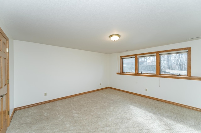 unfurnished room with a textured ceiling and baseboards