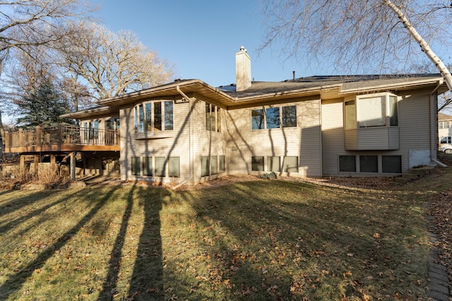 rear view of property featuring a wooden deck, a lawn, and a chimney