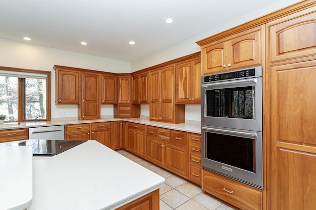 kitchen with brown cabinetry, light countertops, recessed lighting, light tile patterned flooring, and stainless steel appliances