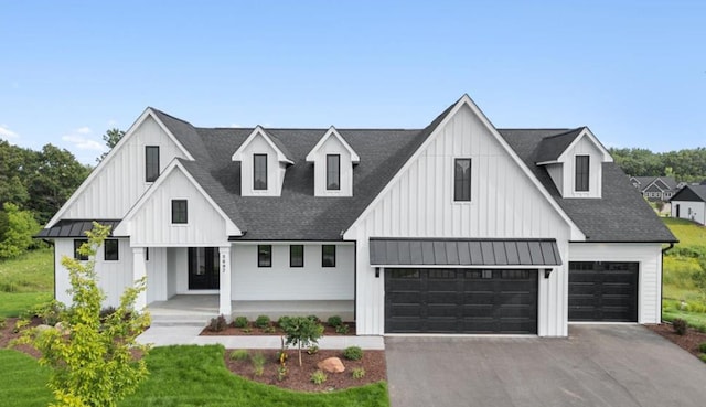 modern farmhouse with a porch, board and batten siding, a standing seam roof, a garage, and driveway