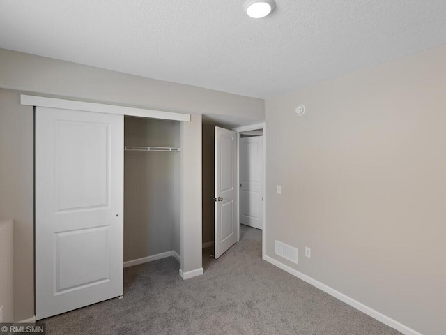 unfurnished bedroom featuring carpet, a closet, visible vents, and baseboards