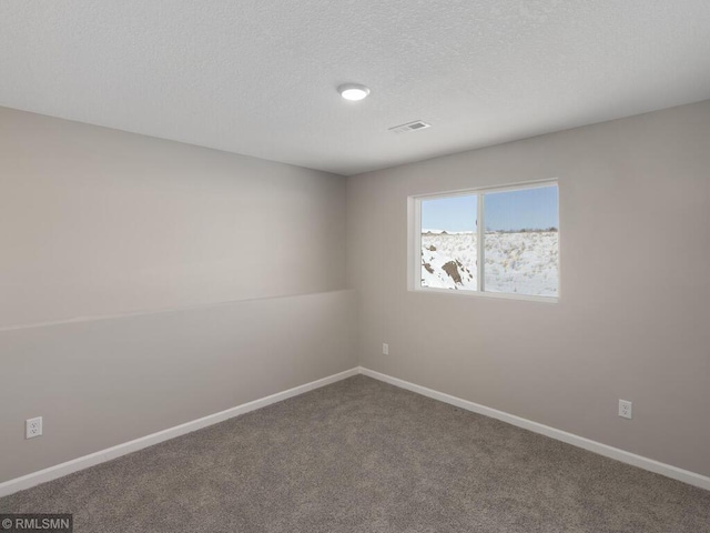 spare room featuring a textured ceiling, carpet floors, and baseboards