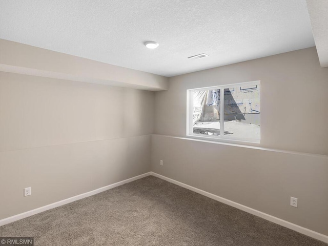 carpeted spare room featuring a textured ceiling, visible vents, and baseboards