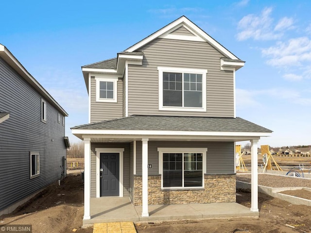 view of front of home featuring a porch, stone siding, and roof with shingles