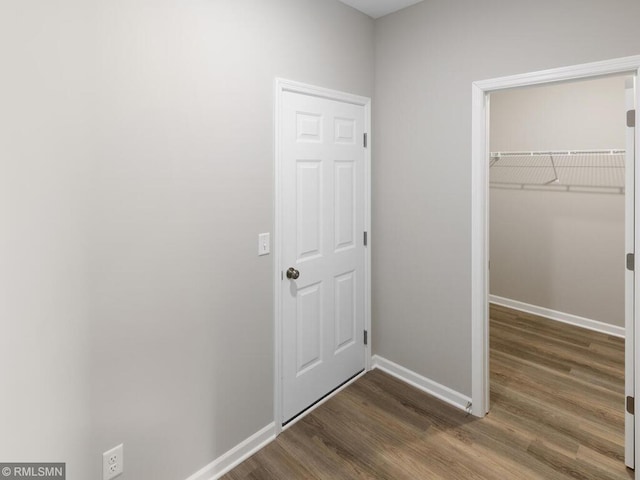 interior space with a closet, baseboards, dark wood finished floors, and a spacious closet