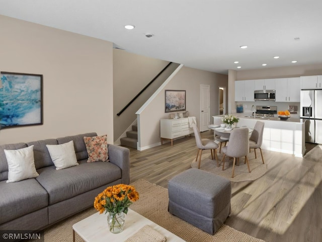 living area featuring recessed lighting, stairway, and light wood-style flooring