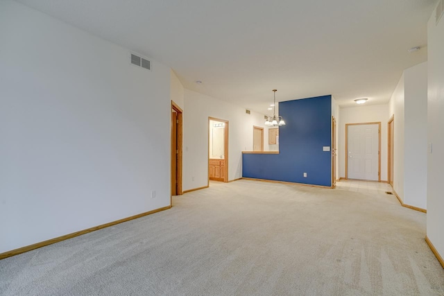 spare room featuring light colored carpet, visible vents, a notable chandelier, and baseboards