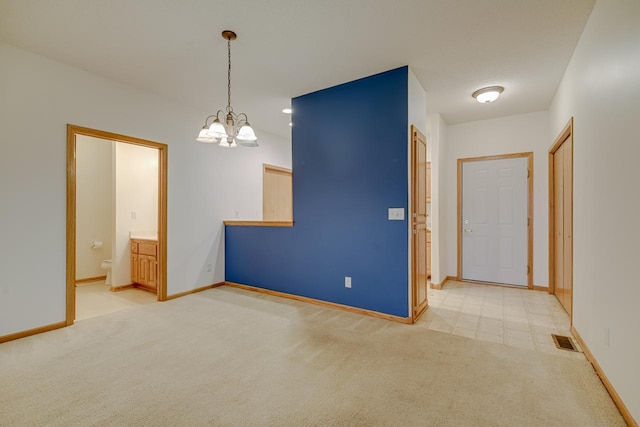 empty room with light carpet, a notable chandelier, visible vents, and baseboards