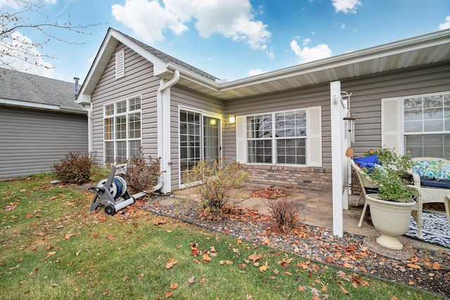 rear view of property with a patio area, brick siding, and a lawn